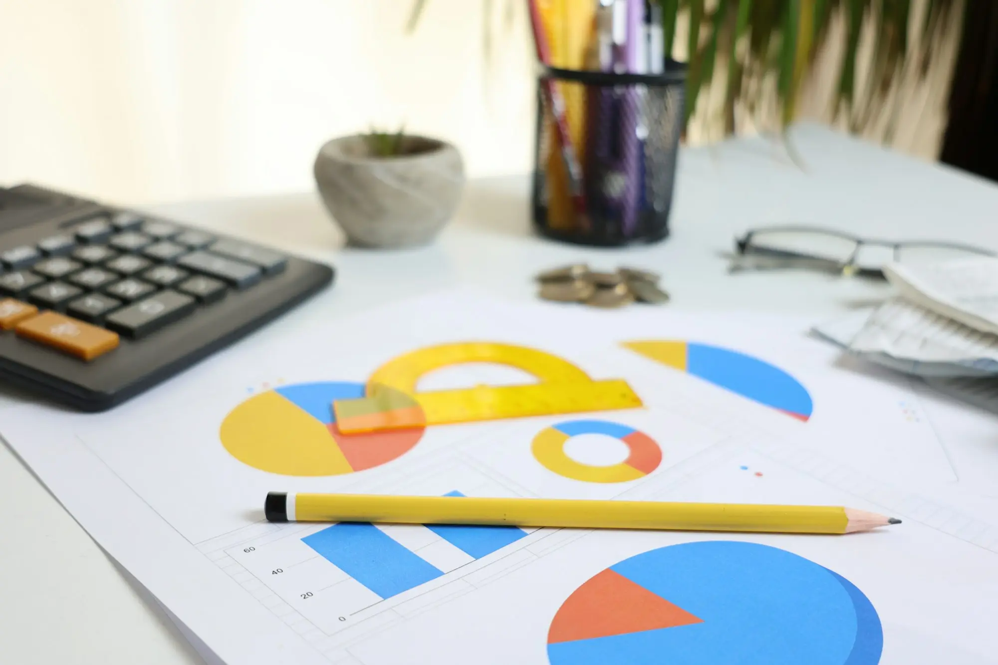Calculator, pie charts, receipts and reading glasses on a small business desk, ready for working out GST on the BAS