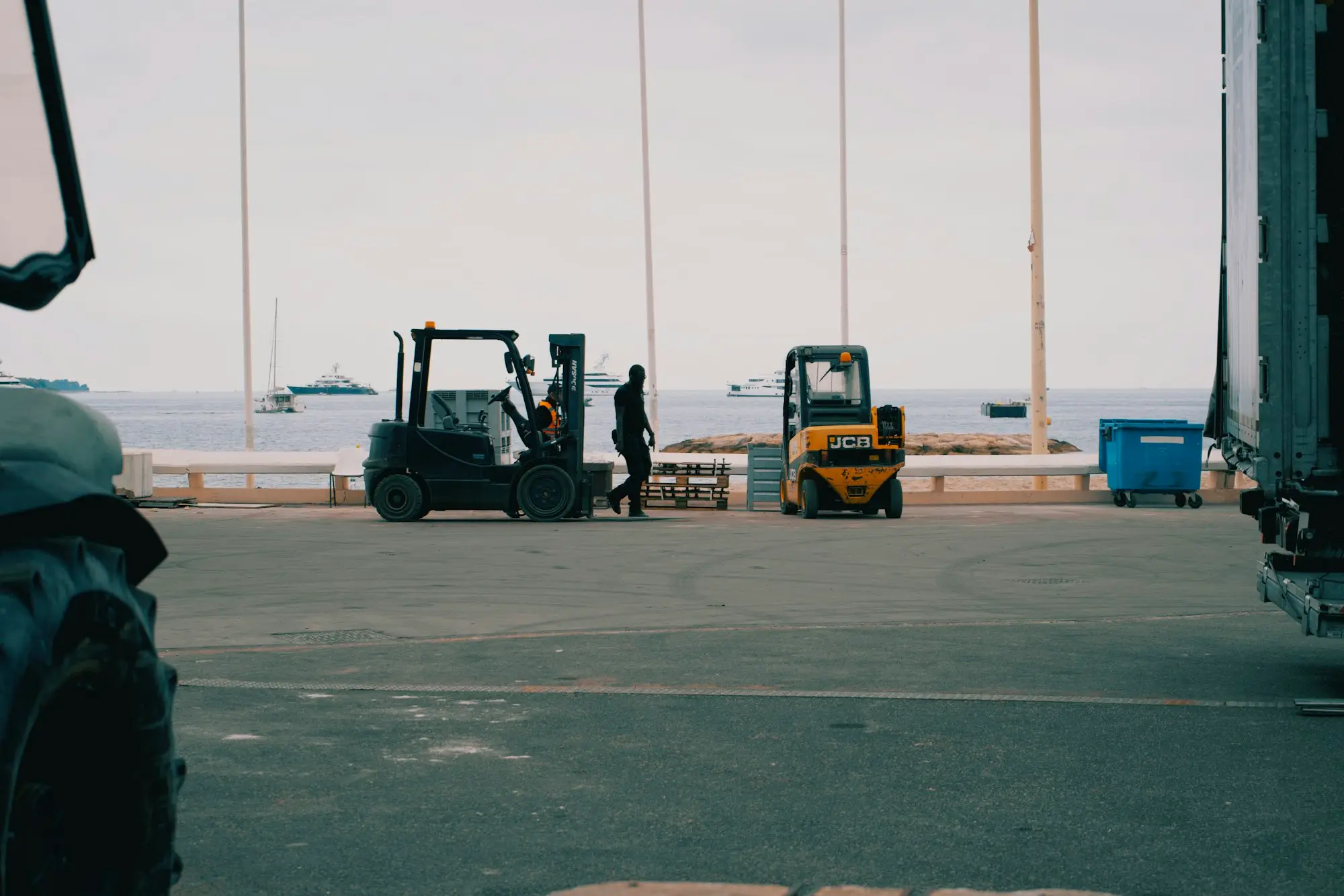 Forklift unloading a new piece of machinery from a truck at a business yard