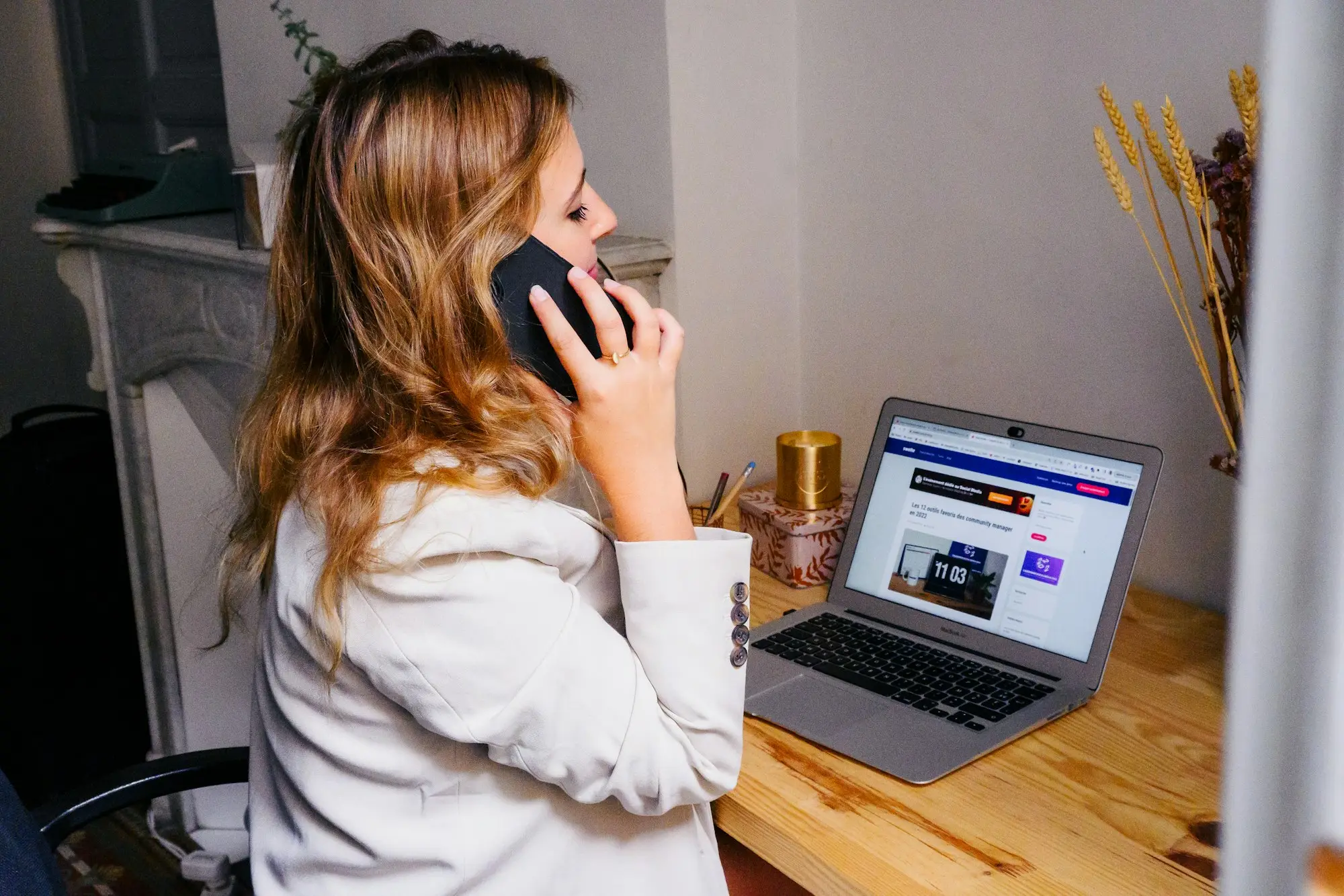 Business owner on a phone call while checking figures on a laptop in a small office
