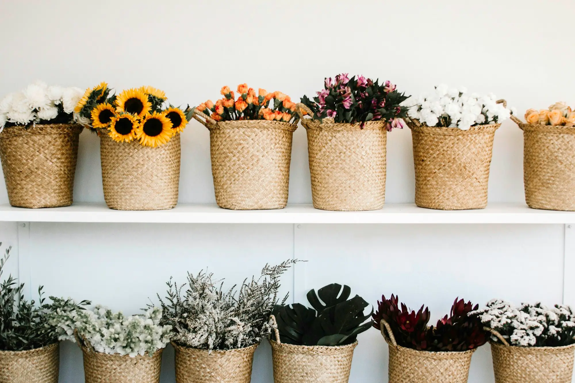 Shelves of flowers in woven baskets in a small retail shop display
